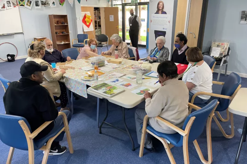 People colouring pictures, playing dominos and knitting at the Dementia hub