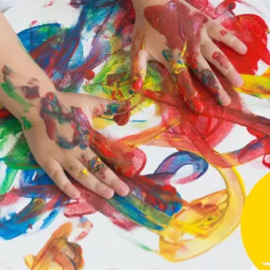 Child is finger painting with colours.