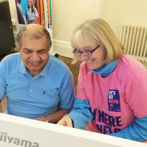 A digital champion volunteer helping a resident on the computer.