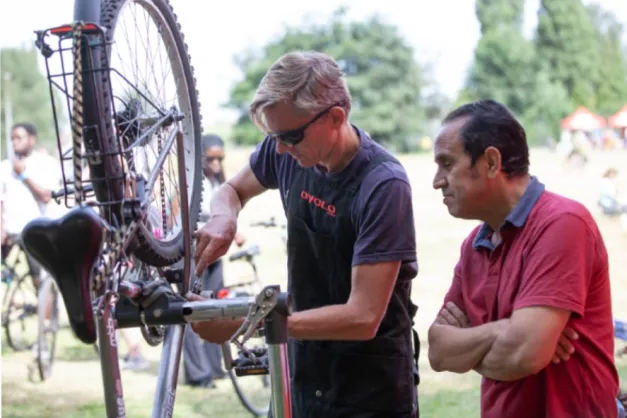 Man repairing a bike with another man onlooking