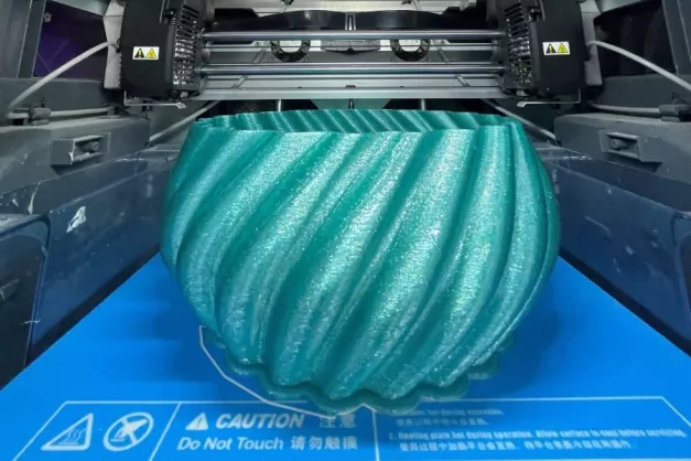 A plastic item in the shape of an ornate bowl is being created by a 3d printer