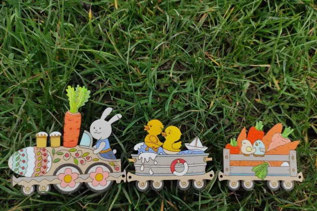 A wooden painted decoration of carrots, rabbits and ducks on a train.