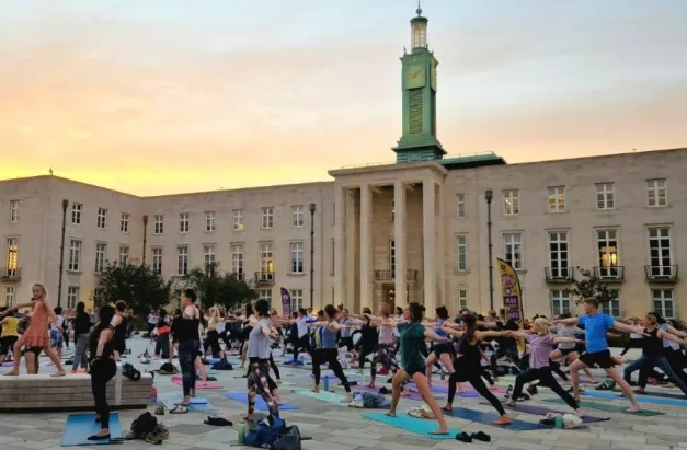 People doing yoga at Fellowship Square with arms outstretched.