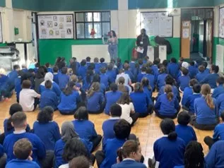 School pupils in blue school uniform sit in assembly