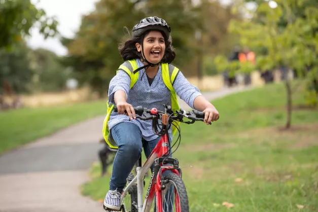 A young girl riding a bike through a park