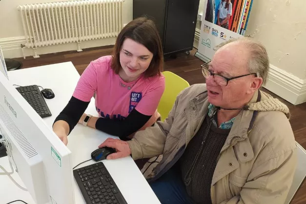 Image of volunteer helping resident on a computer