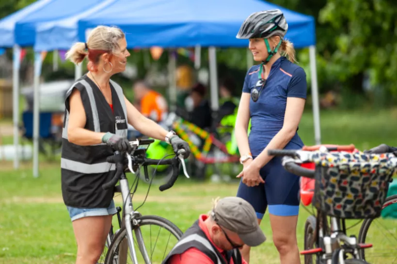 Two ladies having their bikes checked over at an open air event 