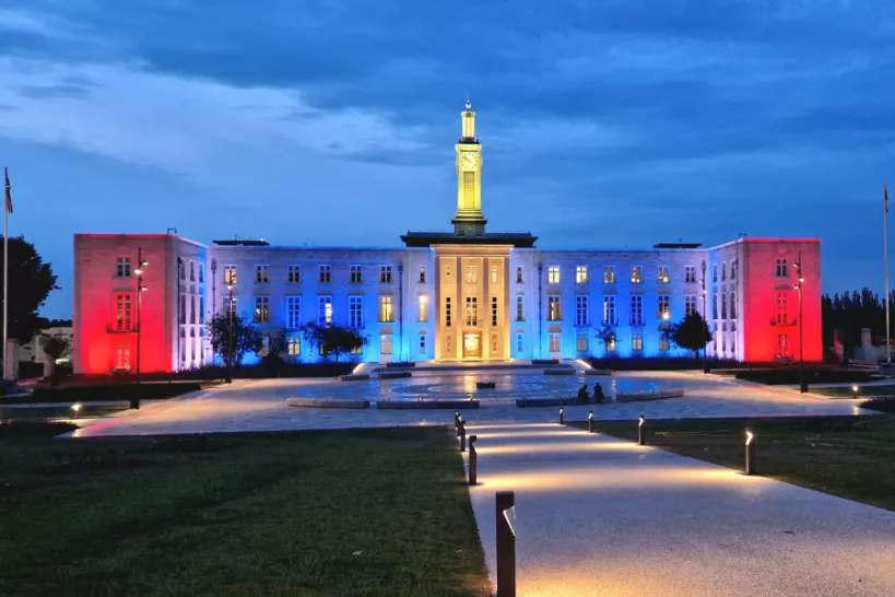 Waltham Forest Town Hall facade lit in the colours of the Antigua & Barbuda flag (red, white, blue and yellow) celebrating Waltham Forest twinning with Antigua & Barbuda during Black History Month 
