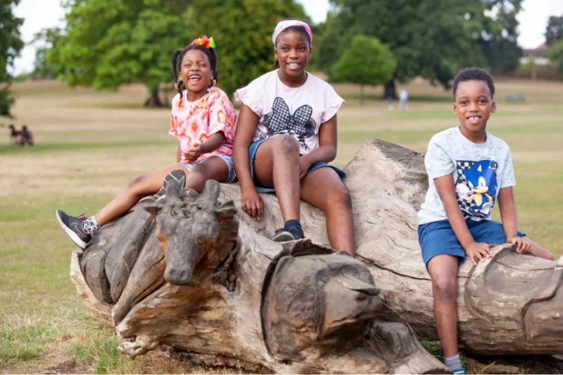 Children smiling on a tree trunk in Highams Park