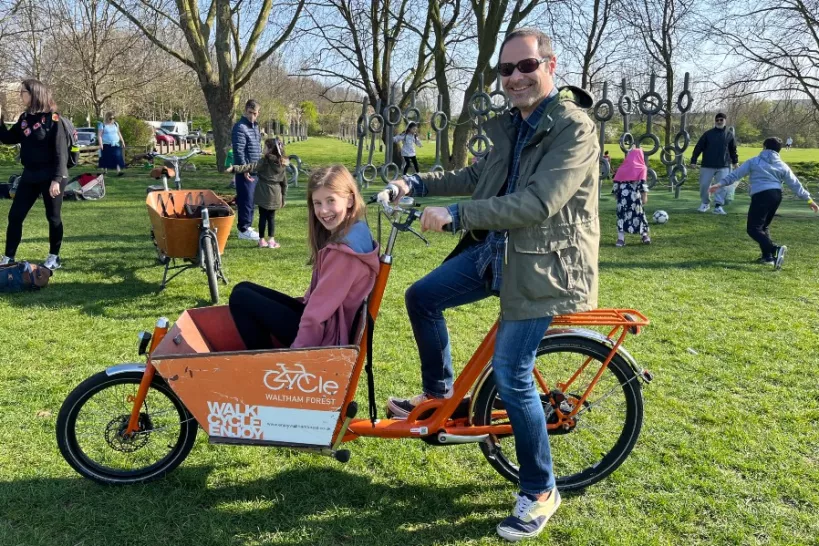 Picture of a man riding a Bakfiets Cargo Bike with a child sitting in the front section.