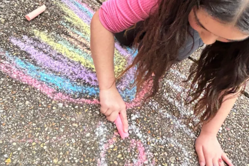 Child is drawing with colourful chalks